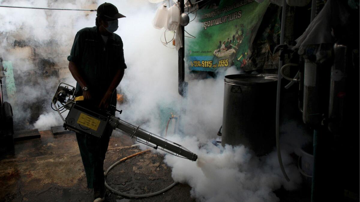 A worker fogs a home with mosquito repellent in Bangkok, Thailand, on June 26, 2013.