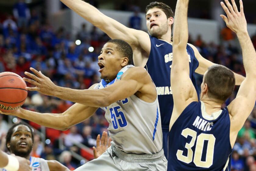 Memphis' Geron Johnson, left, puts up a shot in front of George Washington's Patricio Garino, center, and Nemanja Mikicof during the Tigers' 71-66 win in the second round of the NCAA tournament Friday.