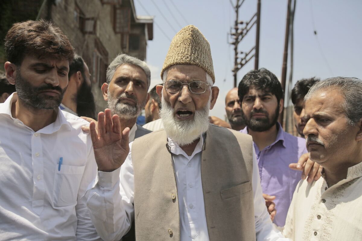 Syed Ali Shah Geelani speaks to the media as he walks outside his house to participate in a march towards the United Nations Military Observer Group office in Srinagar, Indian controlled Kashmir, Friday, July 29, 2016. Geelani, a top separatist leader and one of the severest critics of Indian rule in the disputed Himalayan region of Kashmir, died late Wednesday, Sept. 1, 2021. He was 92. (AP Photo/Mukhtar Khan)