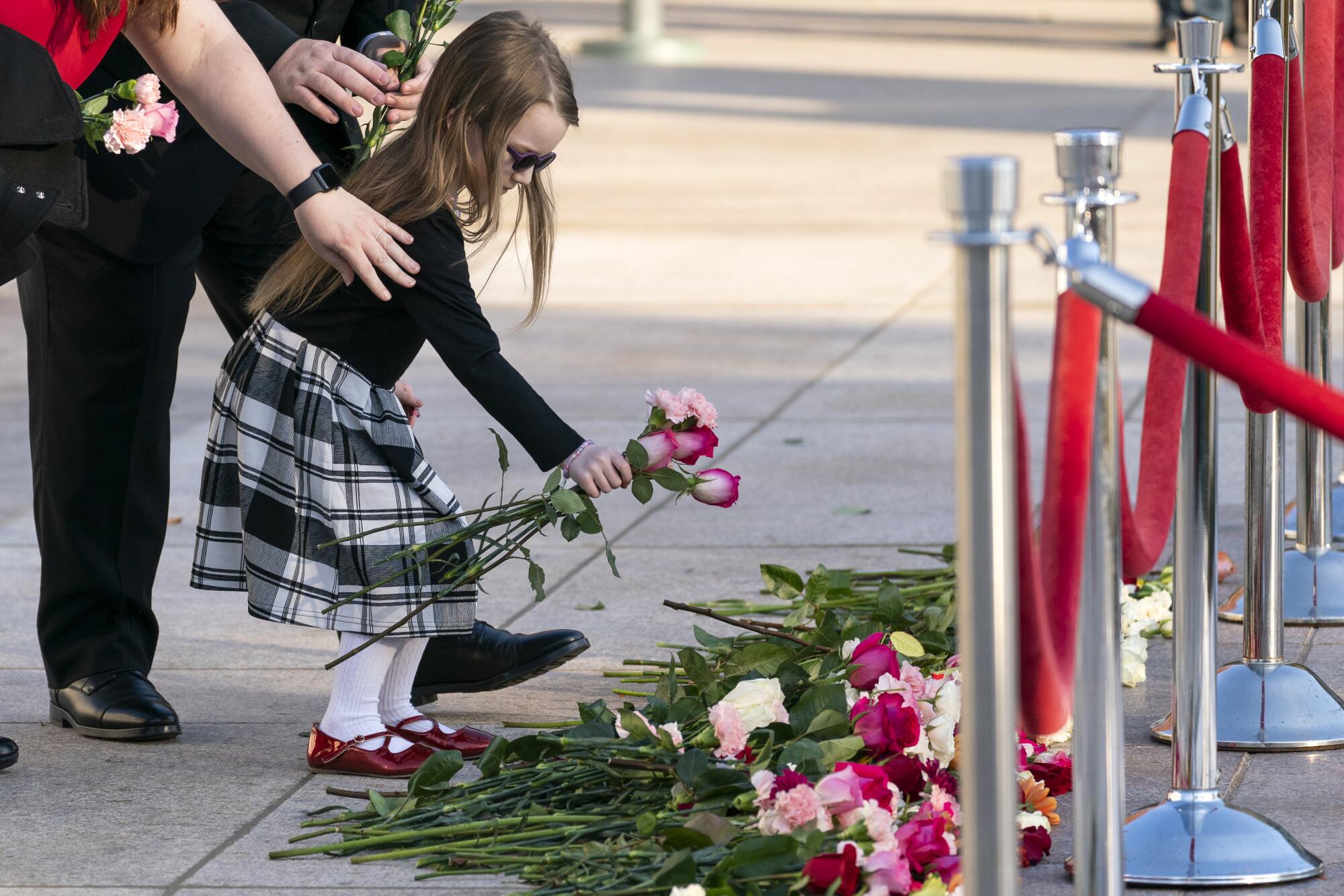 Catalina Brambilla, 4, of Arlington, Va., places flowers 