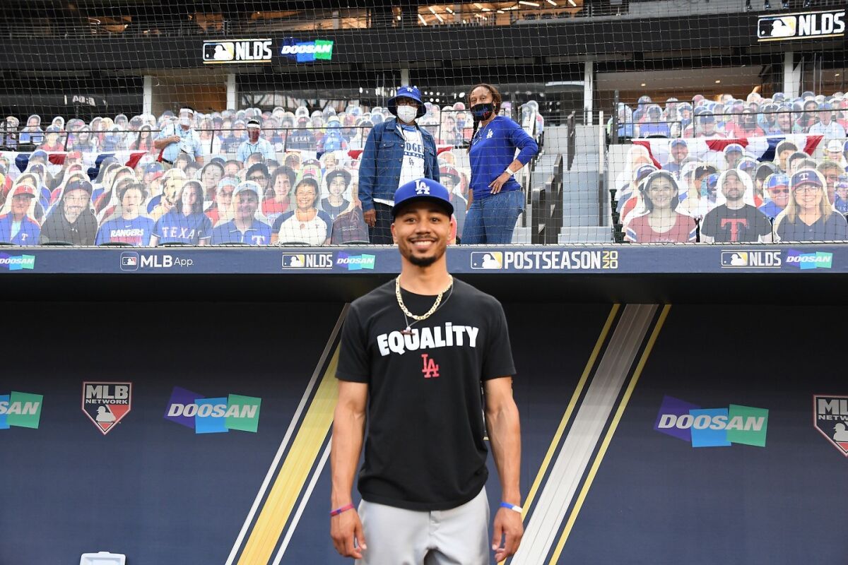 Dodgers right fielder Mookie Betts stands on the field in front of his father, Willie, and mother, Diana.