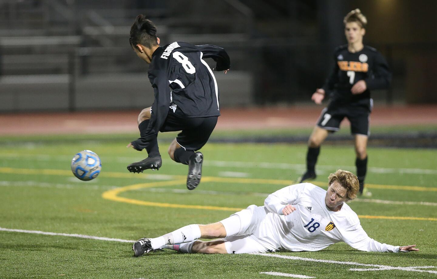 Marina High's Marcus Padilla (18) tackles Huntington Beach's Justin Fujimori as he tries to get the ball out of scoring position during a Wave League boys' soccer match at Cap Sheue Field on Wednesday.