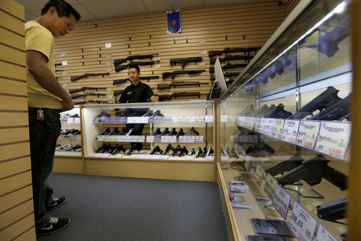 Dennis Lin helps customer Chris Quoc, left, decide which handgun to purchase.