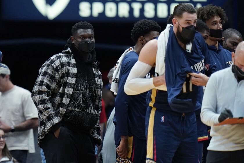 New Orleans Pelicans forward Zion Williamson stands near the bench in street clothes during a timeout in the first half of an NBA basketball game against the Denver Nuggets in New Orleans, Wednesday, Dec. 8, 2021. (AP Photo/Gerald Herbert)