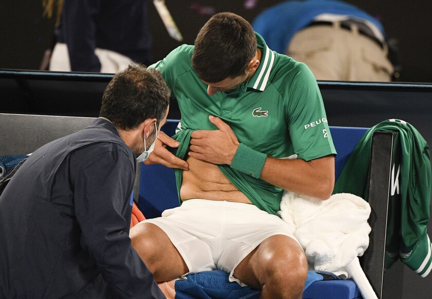 Serbia's Novak Djokovic receives treatment during his third round match against United States' Talyor Fritz at the Australian Open tennis championship in Melbourne, Australia, Friday, Feb. 12, 2021.(AP Photo/Andy Brownbill)