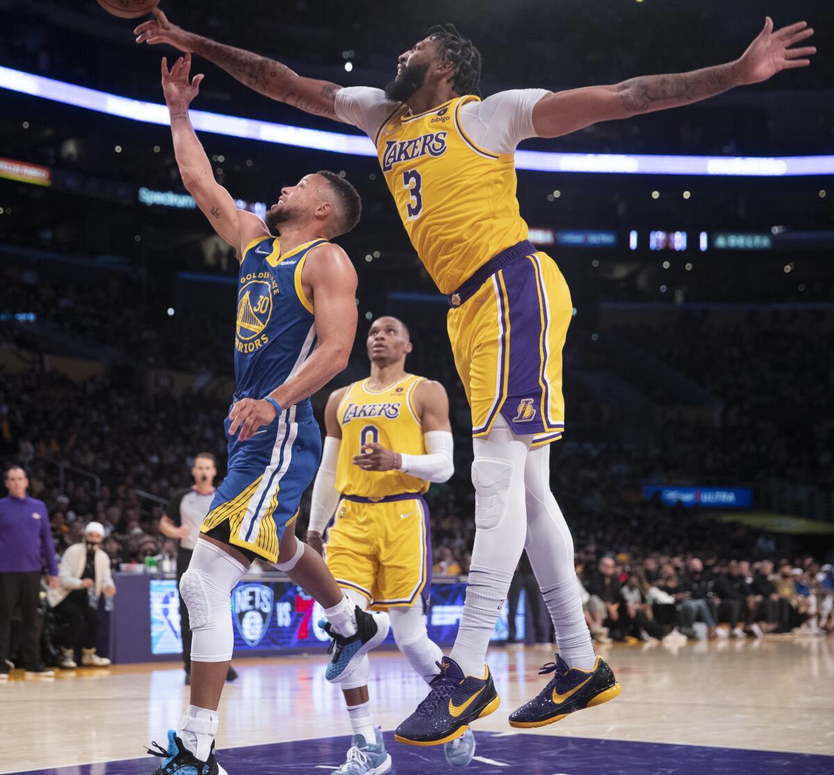 Lakers forward Anthony Davis blocks a layup by Warriors guard Stephen Curry.