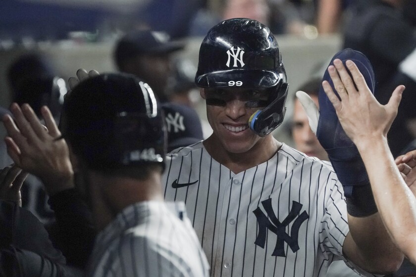 New York Yankees' Aaron Judge high-fives in the dugout after scoring a run in the seventh inning of a baseball game against the Oakland Athletics, Monday, June 27, 2022, in New York. (AP Photo/Bebeto Matthews)
