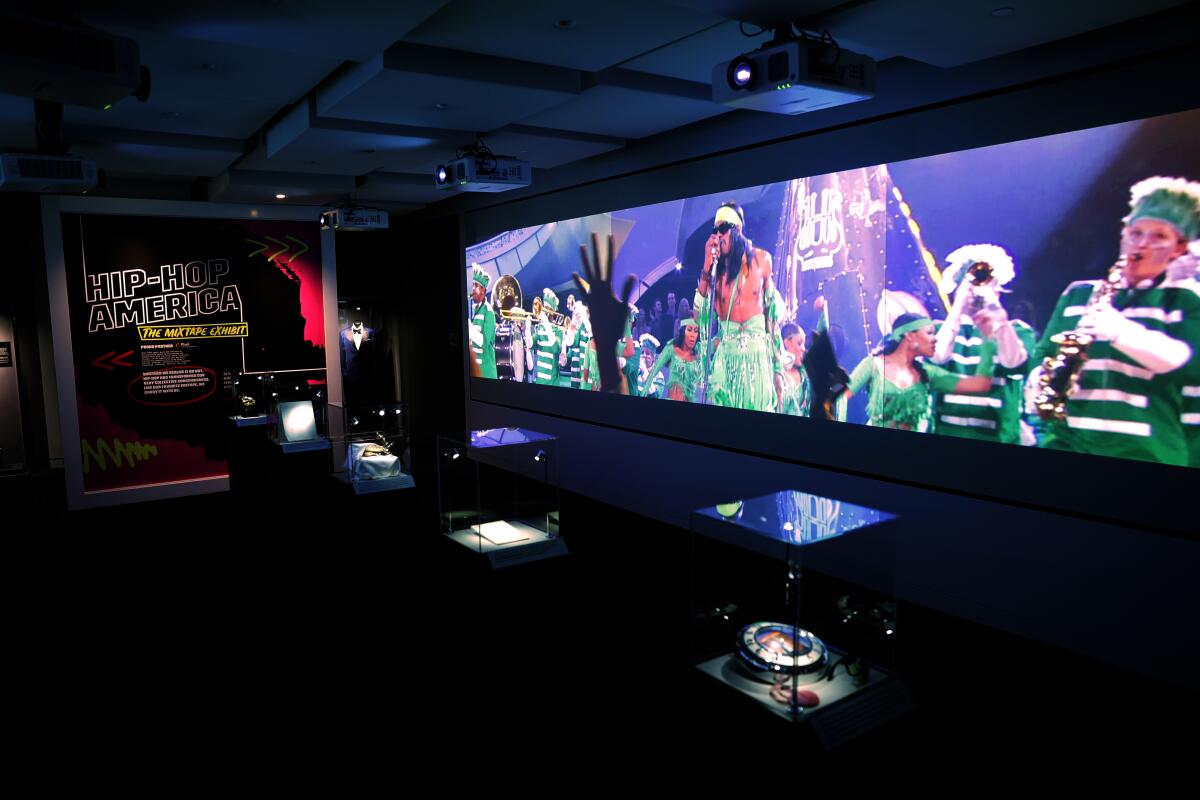 An exhibition of hip hop memorabilia with a performance screened on the wall. 