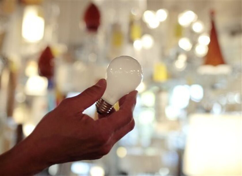 FILE - In this Jan. 21, 2011, file photo, Manager Nick Reynoza holds a 100-watt incandescent light bulb at Royal Lighting in Los Angeles.