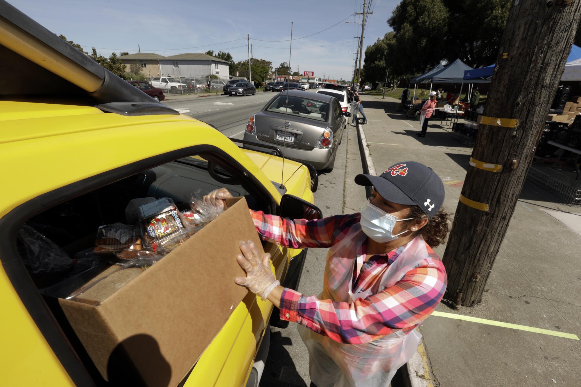 Rocio Bahena hands out boxes of food at Richmond High School, where 6,000 meals were distributed April 22. Bahena normally works as a food service aide in one of the elementary schools. Her husband was laid off and now she is the only provider for her family of four.