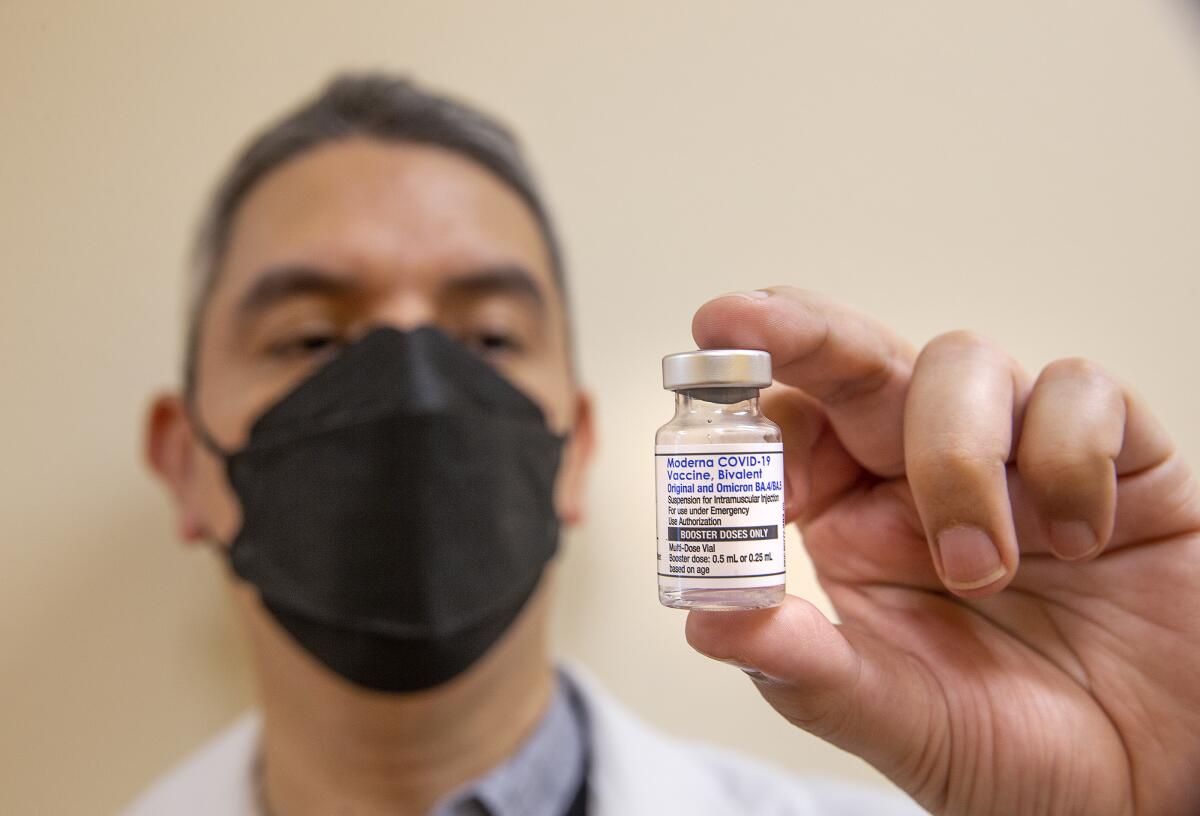A man holds a vial of vaccine. 
