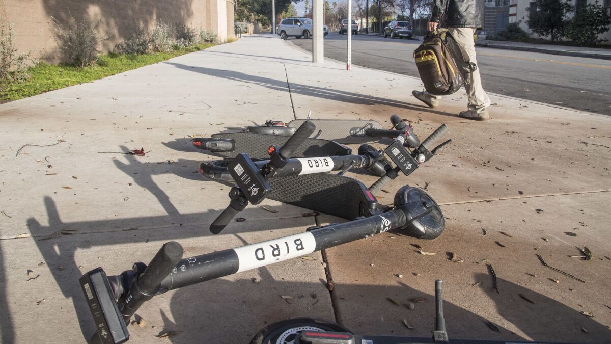 Several Bird scooters are toppled over along the business corridor on Lake Avenue in Altadena.