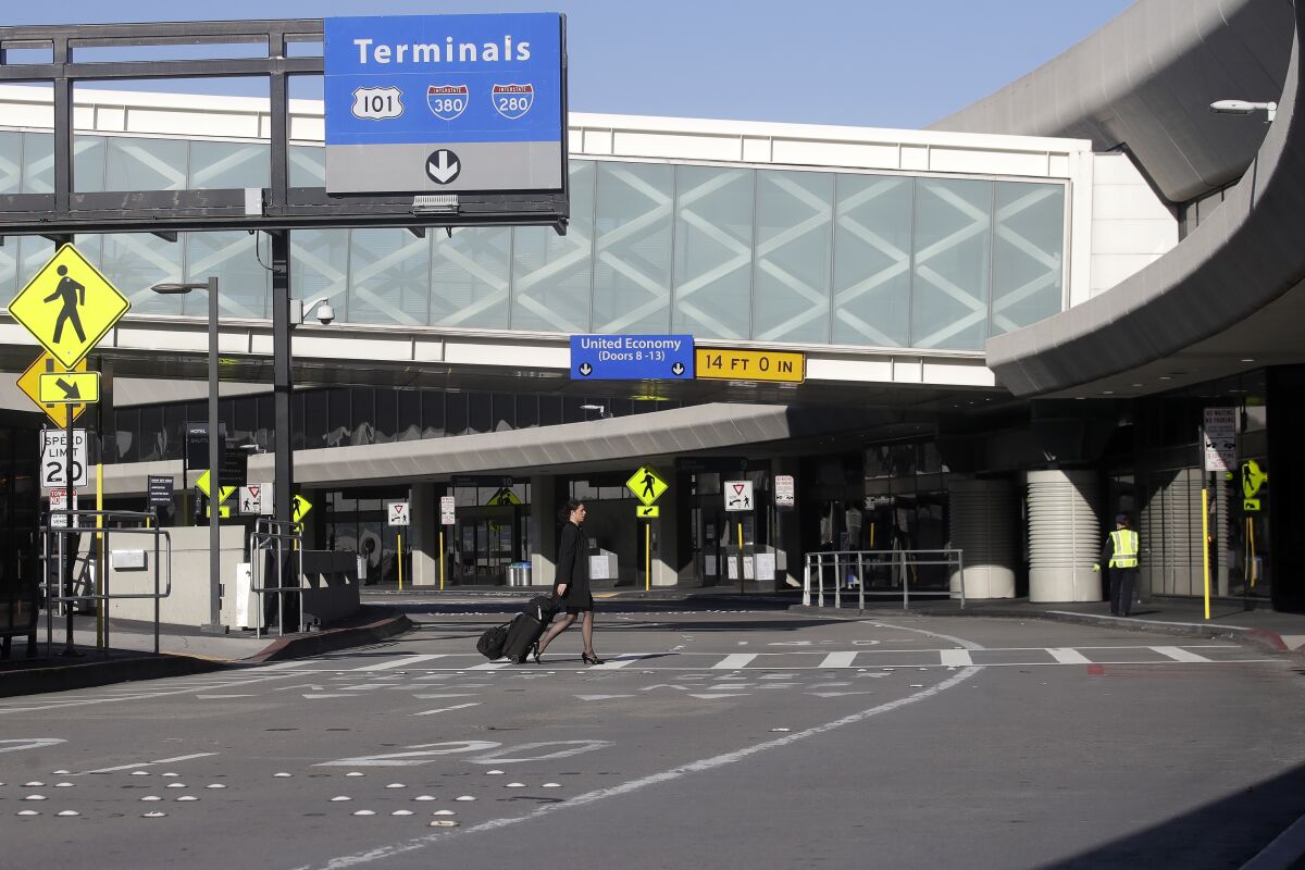A woman crosses a nearly empty road at San Francisco International Airport.