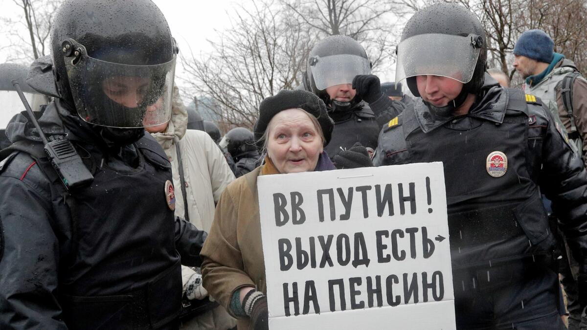 Police detain a woman holding a poster that reads, "Putin, you can retire," at a rally in St. Petersburg, Russia, on April 29, 2017.