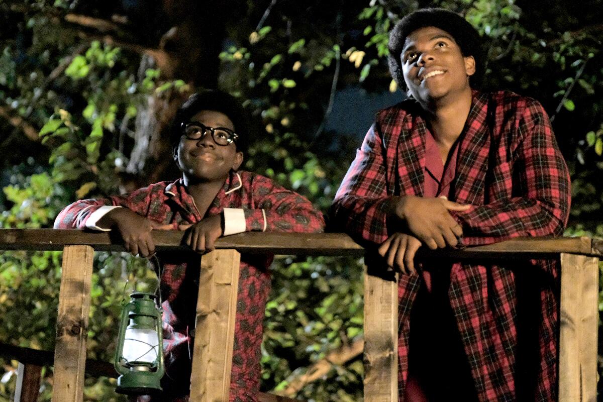 Two boys in plaid pajamas look up at the sky.