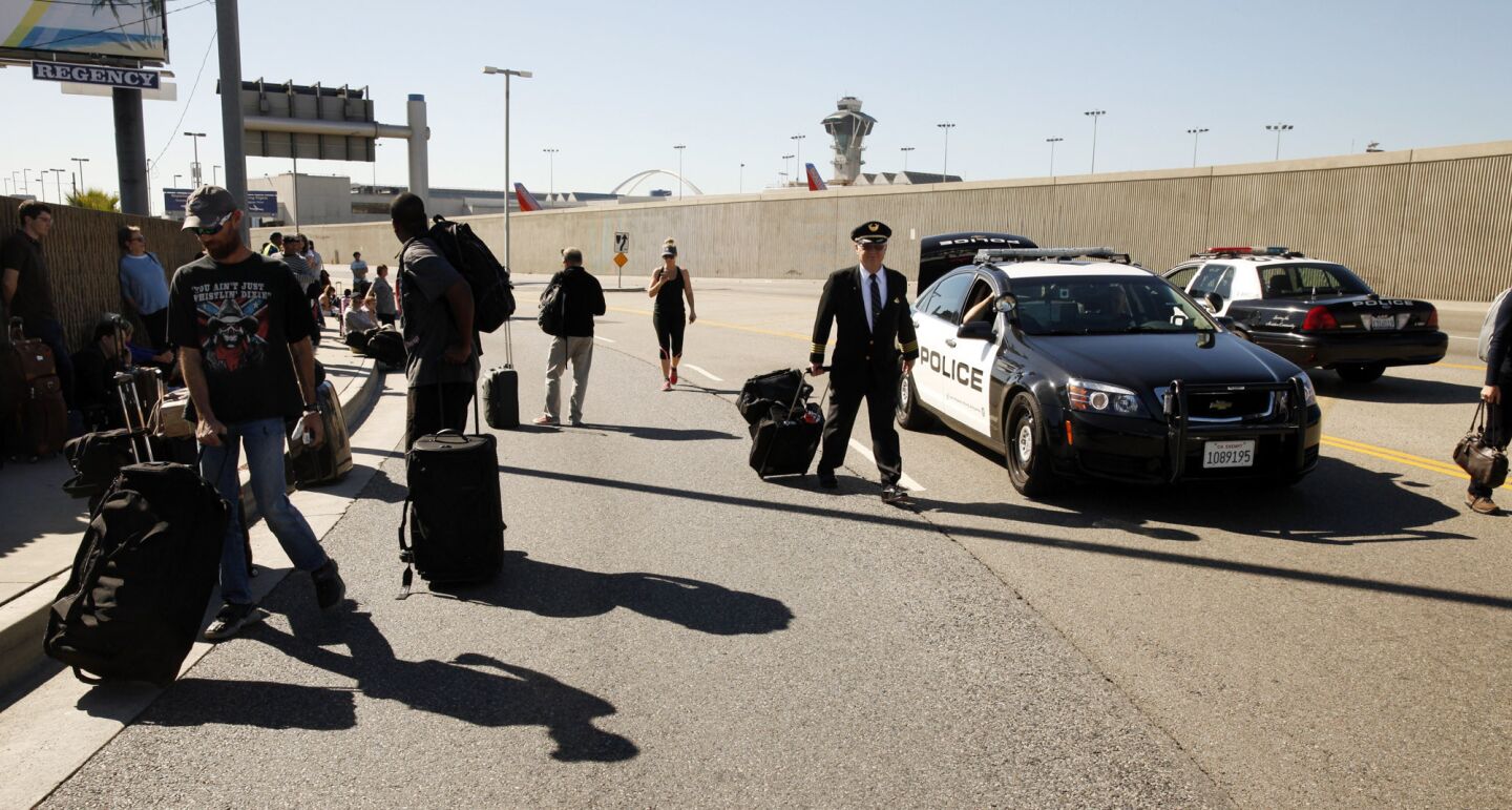 Passengers and airline personnel exit LAX after a Transportation Security Administration agent was shot and killed.