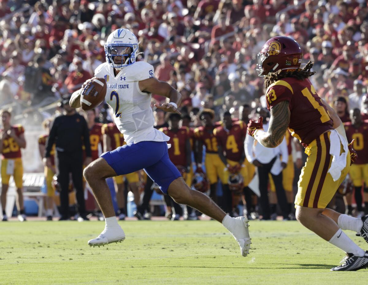 San José State quarterback Chevan Cordeiro is chased by USC linebacker Mason Cobb as he leaves the pocket.