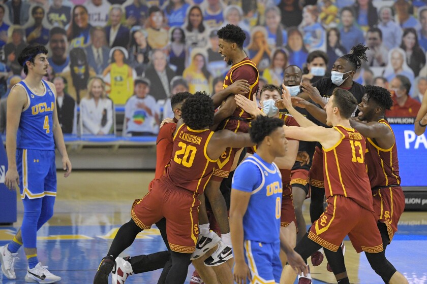 USC guard Tahj Eaddy, top, celebrates with his teammates after hitting a game-winning three-pointer.