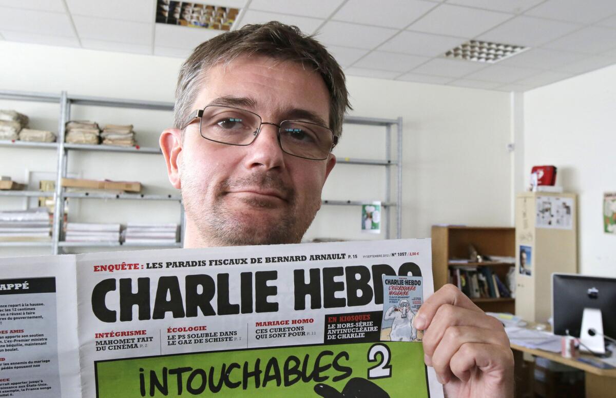 Stephane Charbonnier, also known as Charb, is shown with the front page of Charlie Hebdo in this Sep. 2012 file photo. Charbonnier was among those killed in the shooting at the magazine's offices in January.