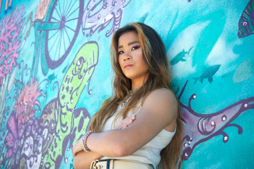 Newport Beach based musician Kitty Noir poses for a photo next to a mural outside of 20th Street Beach and Bikes Tuesday, April 2, a few days ahead of setting out on her first tour of shows.