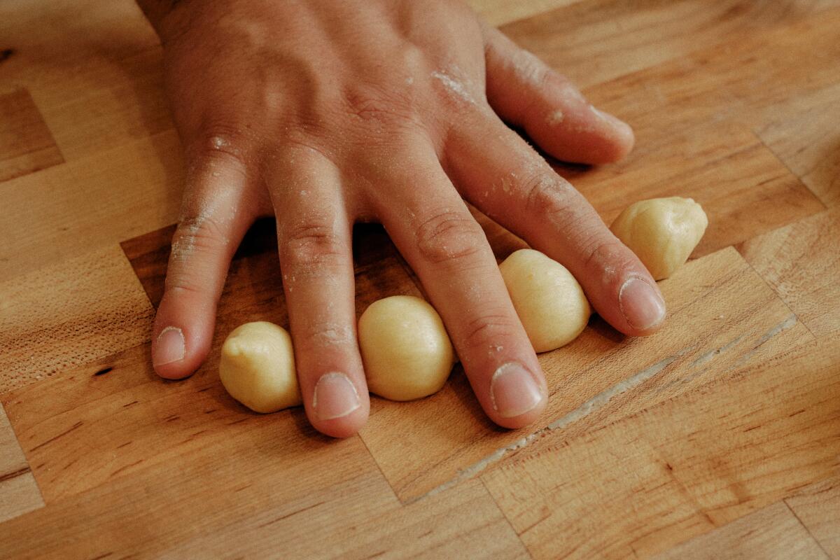 Enciso's fingers alternate with four dough "knobs" that will make bones on the pan de muerto