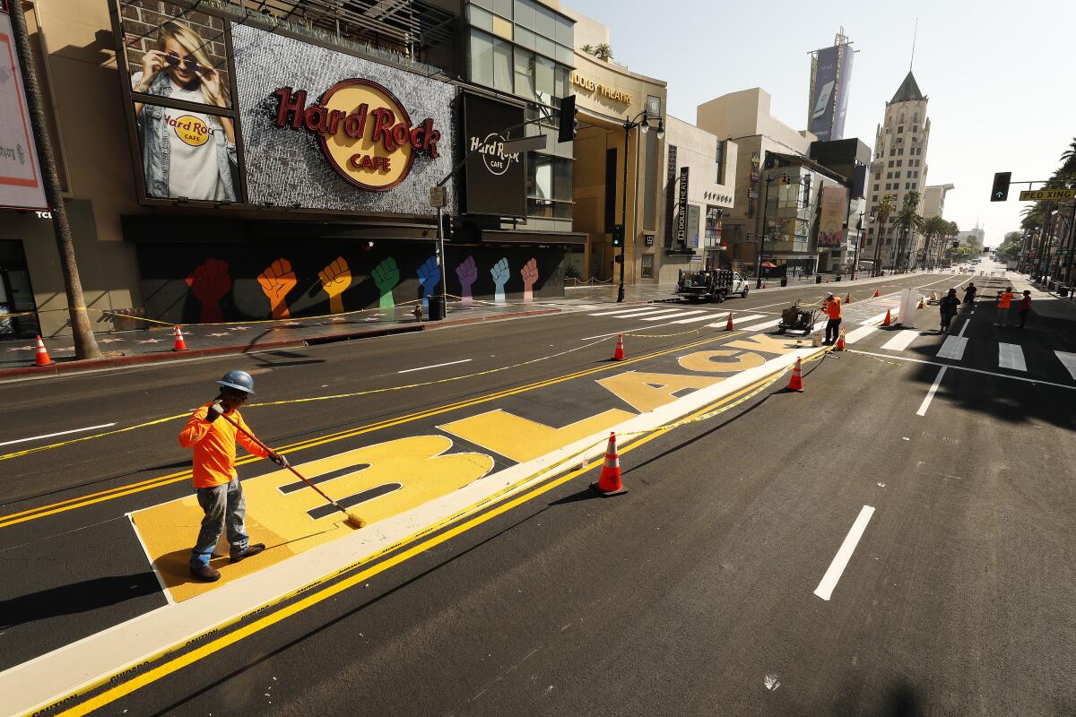 Jaime Garcia paints the colors on the permanent 'All Black Lives Matter' street mural in the middle of Hollywood Blvd.