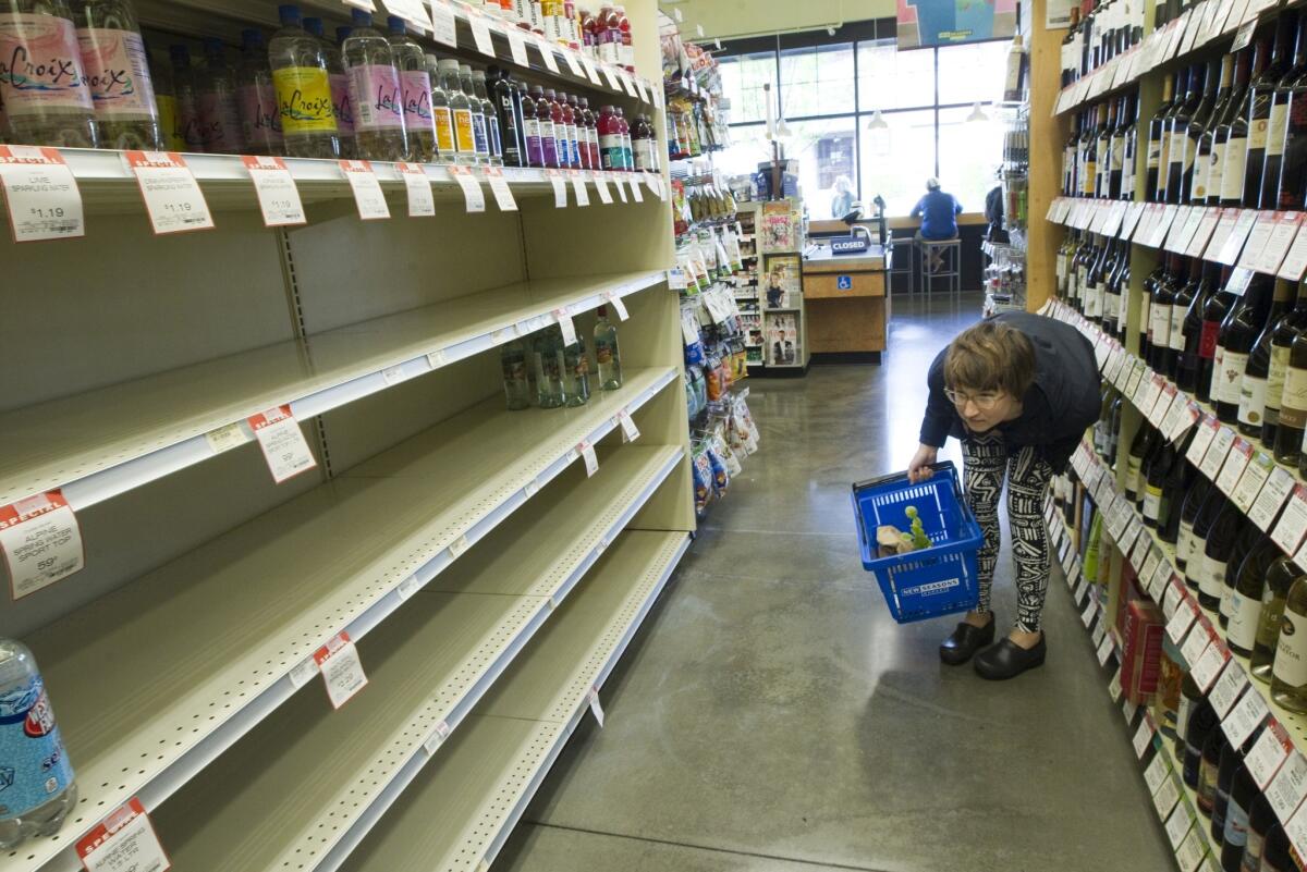 A shopper looks for bottled water on nearly empty shelves at a New Seasons Supermarket in Portland, Ore. The city issued a boil-water alert after samples found E. coli contamination.