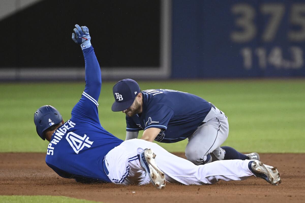 Toronto Blue Jays' George Springer (4) slides into second base with a double ahead of the tag by Tampa Bay Rays' Brandon Lowe during the fourth inning of a baseball game Tuesday, Sept. 14, 2021, in Toronto. (Jon Blacker/The Canadian Press via AP)