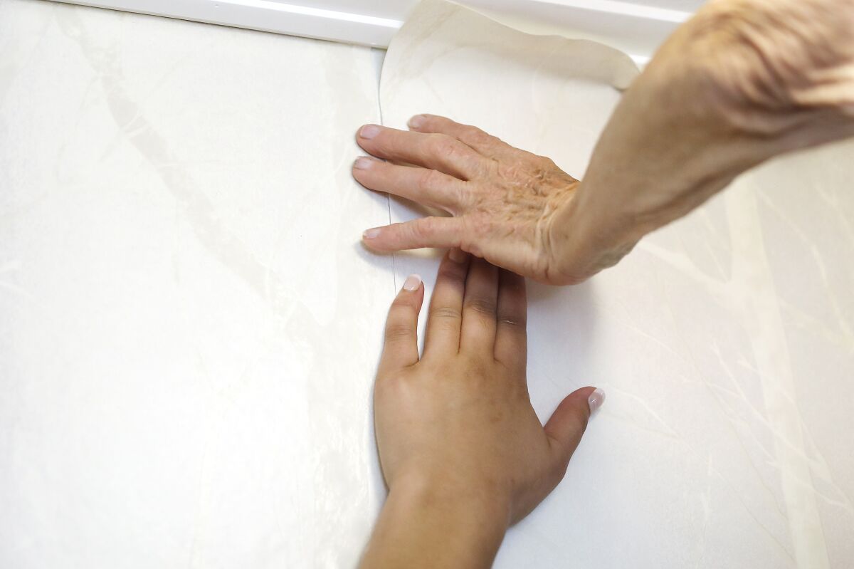 Reita Green, right, and Beverly Pate smooth out wallpaper at a client's home. 