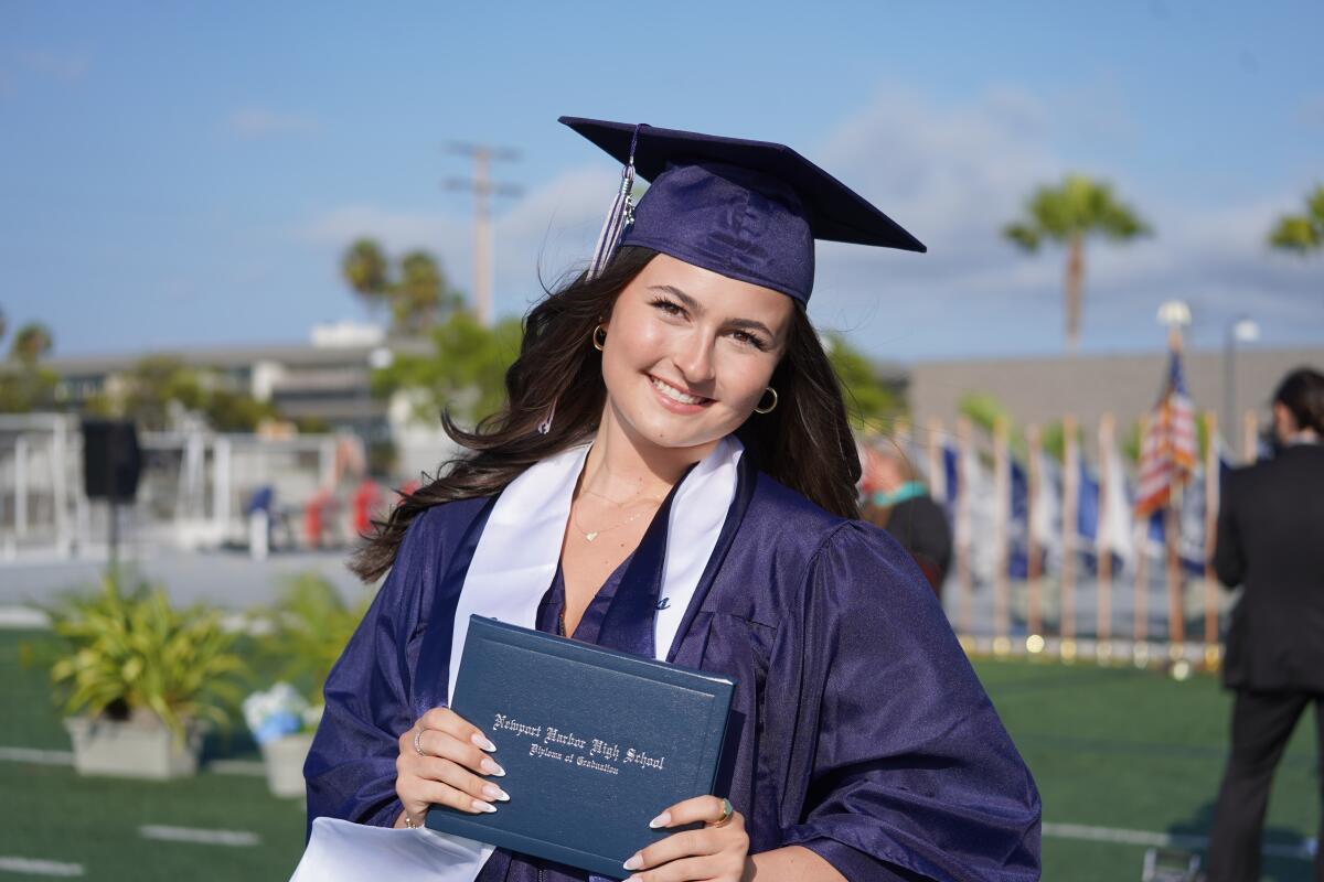 A member of the Class of 2025 from Newport Harbor High School is all smiles as she holds her diploma.