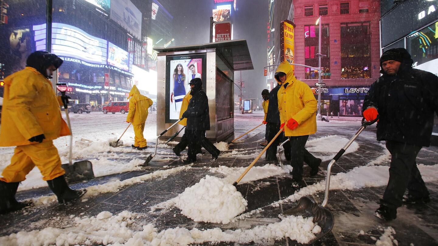 A crew of snow shovelers work as a snowstorm sweeps through Times Square on March 14, 2017, in New York.