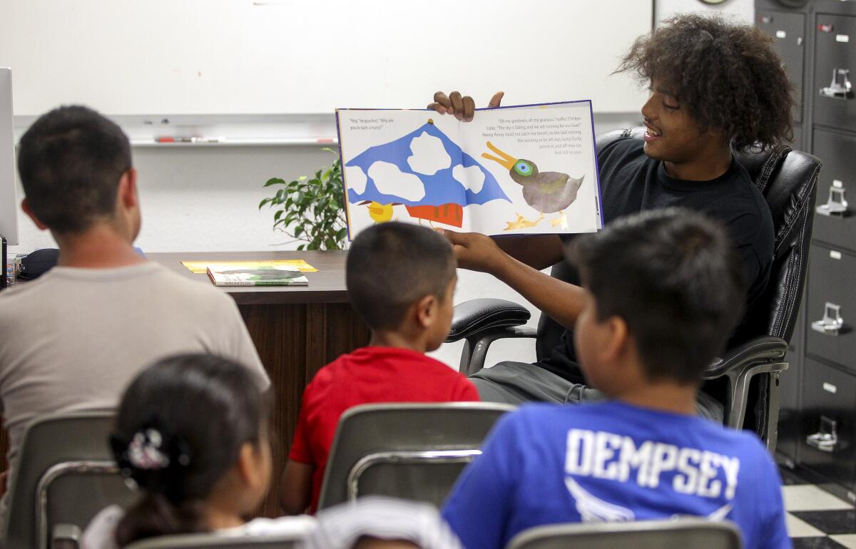 Jerry Riggings Jr. 16, son of the the owner of Urban Barber College, reads "Chicken Little" to children during the Summer Time is Reading Time in the Diamond, a children's book read-aloud, at Urban Barber College on Wednesday, July 10, 2019 in San Diego, California.