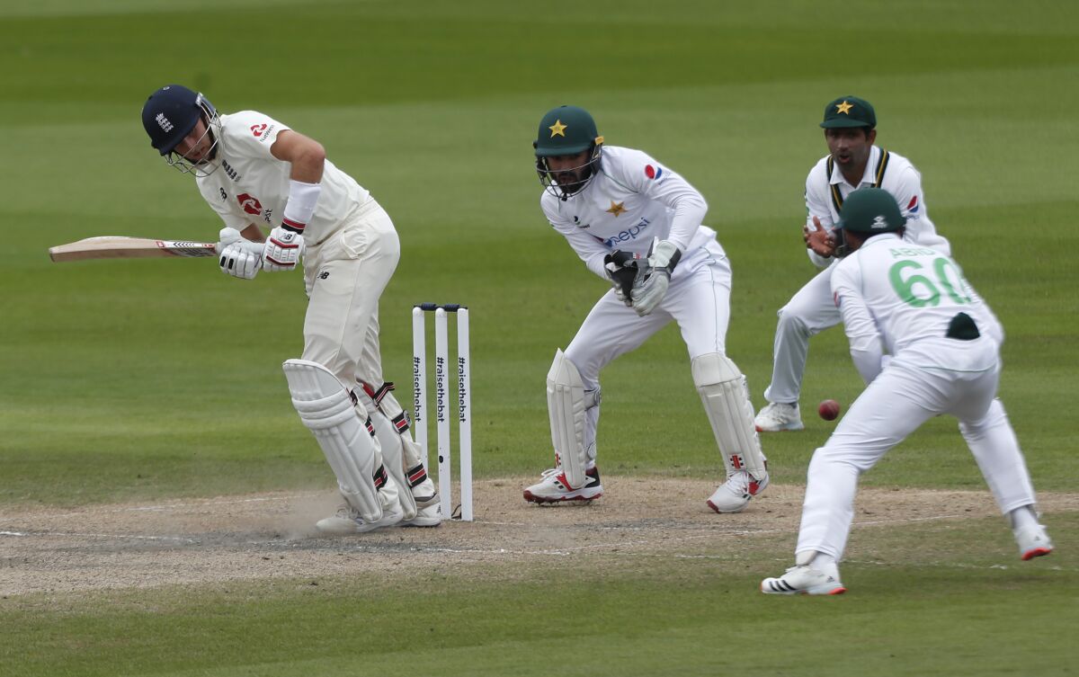 England's captain Joe Root, left, plays a shot during the fourth day of the first cricket Test match between England and Pakistan at Old Trafford in Manchester, England, Saturday, Aug. 8, 2020. (Lee Smith/Pool via AP)