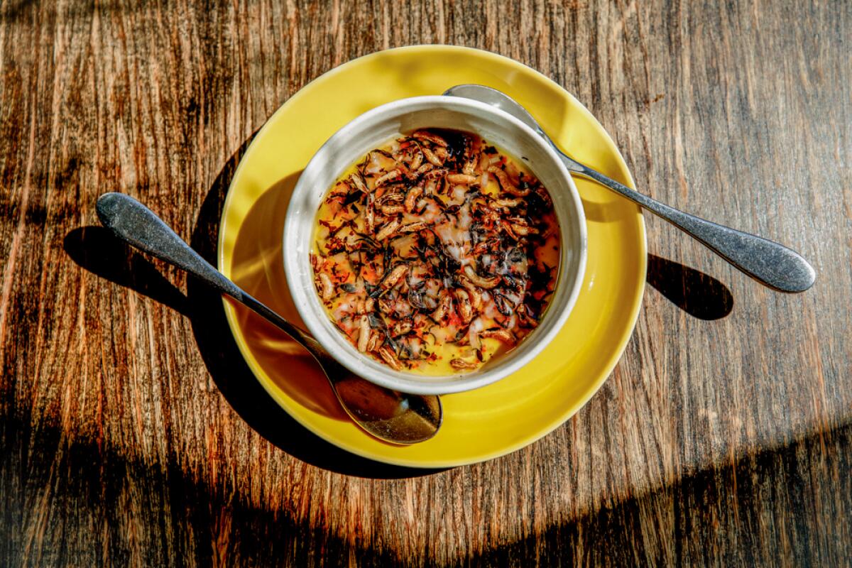 Uni panna cotta is served in a bowl set on a plate with two spoons