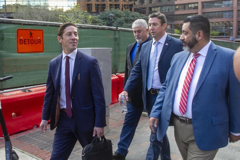 Former US Representative Duncan Hunter, second from right, , walks towards Broadway after leaving through the back door of the Federal courthouse in San Diego, CA on March 17th after being sentenced to 11 months in Federal Prison after pleading guilty to a single count related to campaign fraud.