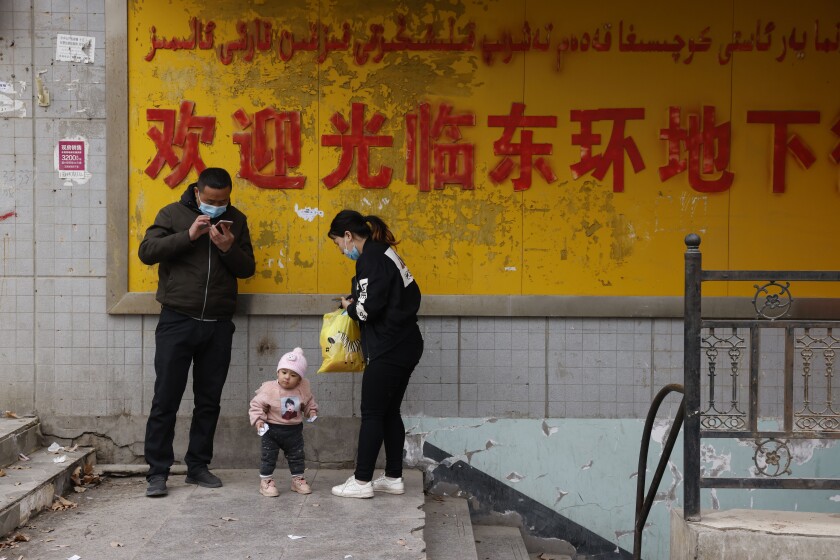 A family stands at the entrance to an underground retail street in Aksu in western China's Xinjiang Uyghur Autonomous Region on March 18, 2021. China is going global with its campaign to deflect criticism over its policies in the northwestern region of Xinjiang. The region's government on Wednesday, June 2, organized a transcontinental zoom call showcasing economic development and poverty elimination. (AP Photo/Ng Han Guan)