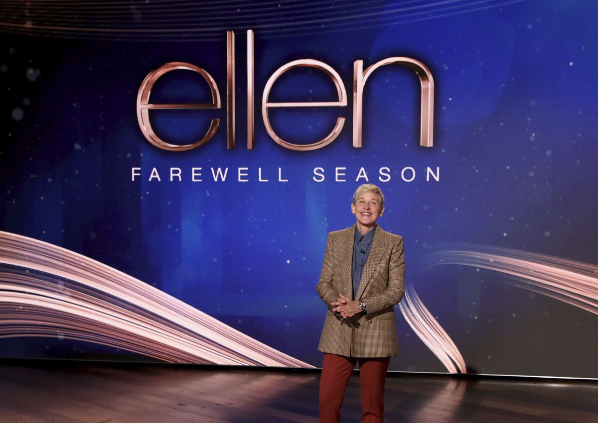 A talk show host appears onstage in front of a screen that says 'Ellen Farewell Season'
