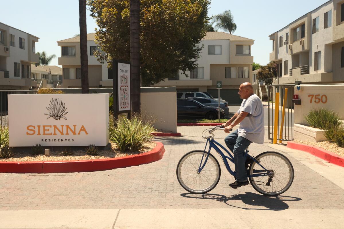 A man rides his bike by the Sienna Residences in Pomona, Calif.