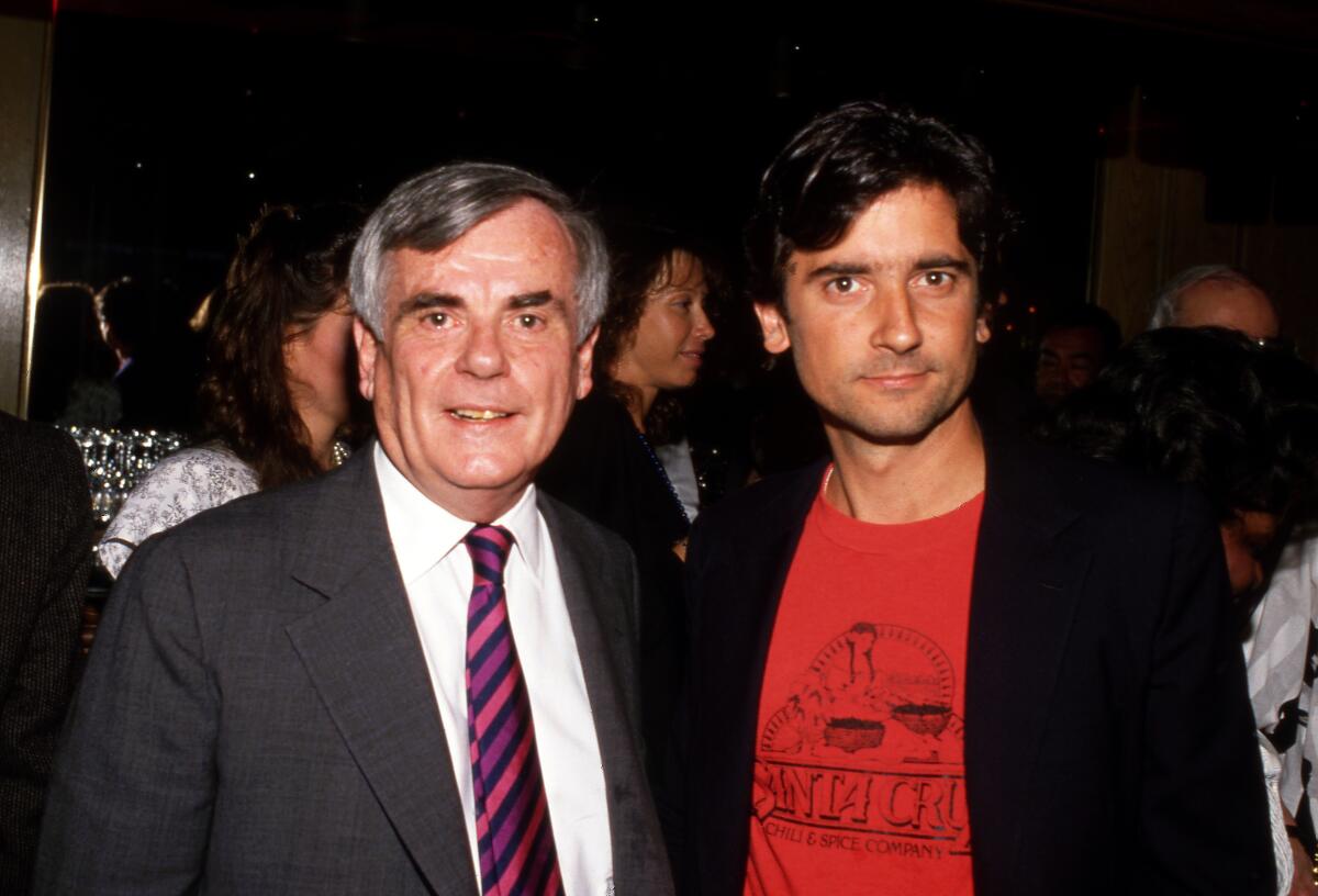 Dominick Dunne, in a suit and tie, and Griffin Dunne, in a red T-shirt and blazer, stand side by side.