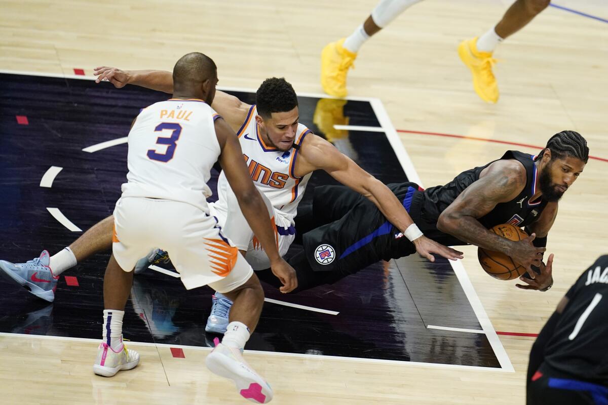 Clippers guard Paul George, right, recovers a loose ball in front of Phoenix Suns guards Devin Booker and Chris Paul.