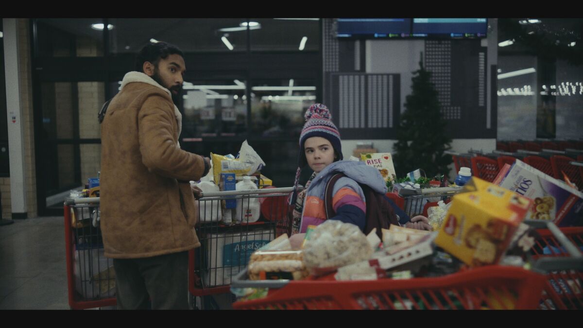 A man and a young girl loading up on groceries in winter.