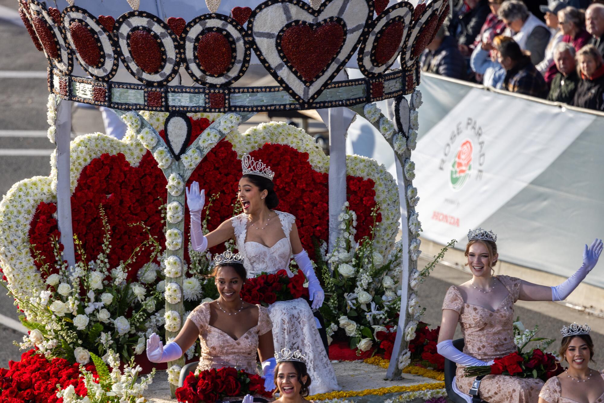 Rose Queen Naomi Stillitano and members of her court wave in the Rose Parade.