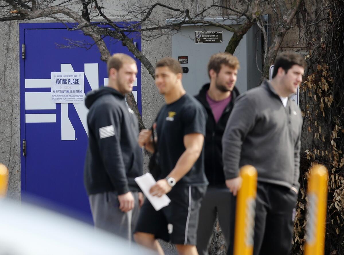 A group of Northwestern football players stands outside McGaw Hall, where voting is taking place Friday on the formation of the nation's first union for college athletes.
