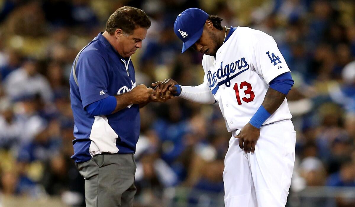Dodgers trainer Stan Conte examines the right hand of shortstop Hanley Ramirez after he was struck by a ball hit by Colorado's Corey Dickerson in the seventh inning Tuessay night.