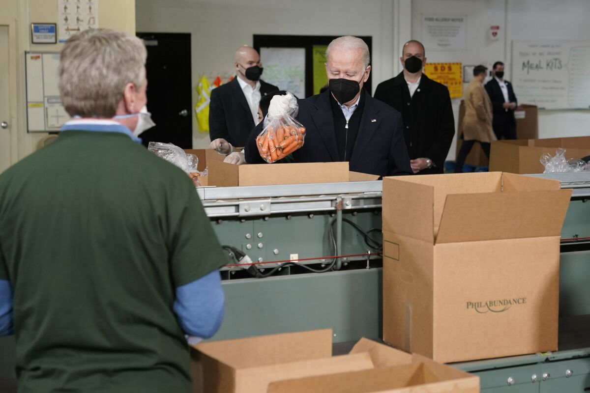 President Joe Biden packs produce while volunteering at hunger relief organization Philabundance, Sunday, Jan. 16, 2022, in Philadelphia. (AP Photo/Patrick Semansky)
