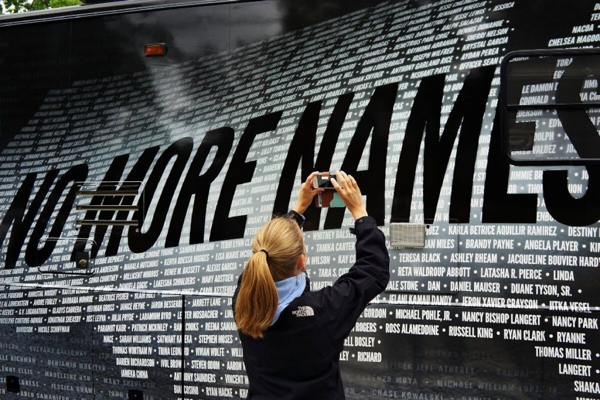 Lindsay Knauf takes a picture of a bus bearing some of the more than 6,000 names of people killed by gun violence since the massacre in Newtown, Conn.