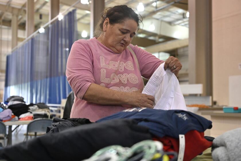 Evelyn Smith of Cary, Ky., gathers clothing at the Knott County Sportsplex in Leburn, Ky., Friday, July 29, 2022. Smith lost everything as fast rising floodwaters forced her from her home, and the sportsplex is being used as a evacuation center. (AP Photo/Timothy D. Easley)