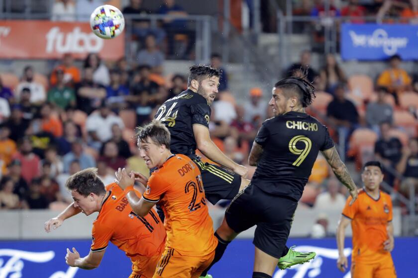 Los Angeles FC forward Cristian Arango (9) headers the ball into the goal to score past midfielder Ryan Hollingshead (24) and Houston Dynamo forward Corey Baird (11) and midfielder Griffin Dorsey (25) during the first half of an MLS soccer match Wednesday, Aug. 31, 2022, in Houston. (AP Photo/Michael Wyke)