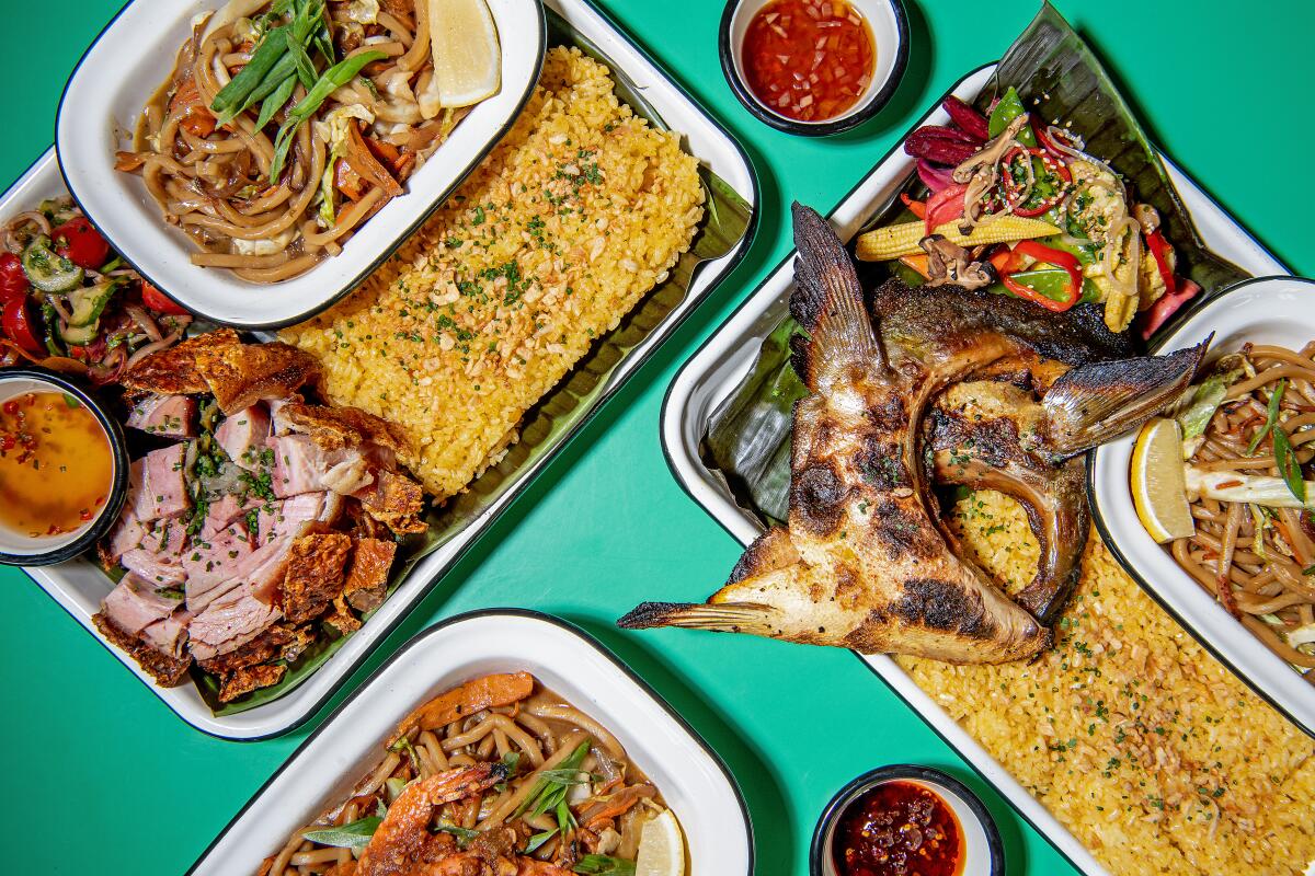 A spread of fish collar, pancit , lechon and more from Kua Lord on a blue-green tabletop.