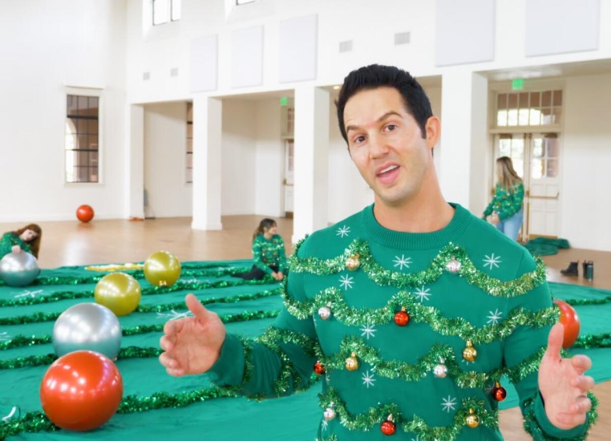 Evan Mendelsohn, co-founder of Tipsy Elves, wears a human-size version of the ugly Christmas super sweater his company made.